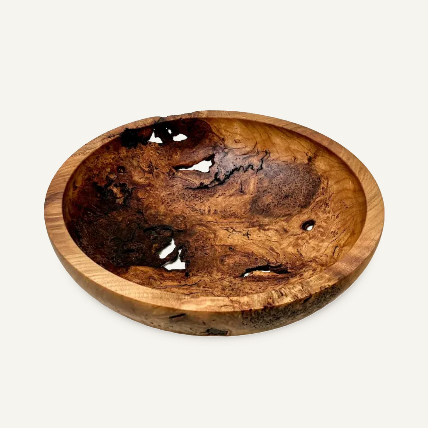 Hand-turned cherry burl bowl with natural voids and varied grain, viewed from above at an angle