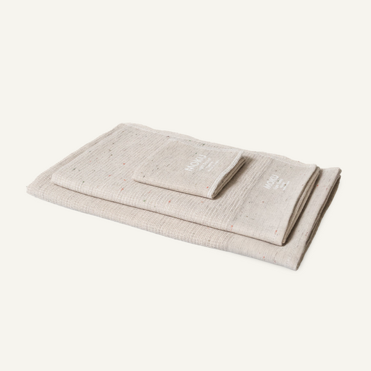 Three folded Moku Light Towels in natural speckled cotton, stacked with the smaller size on top