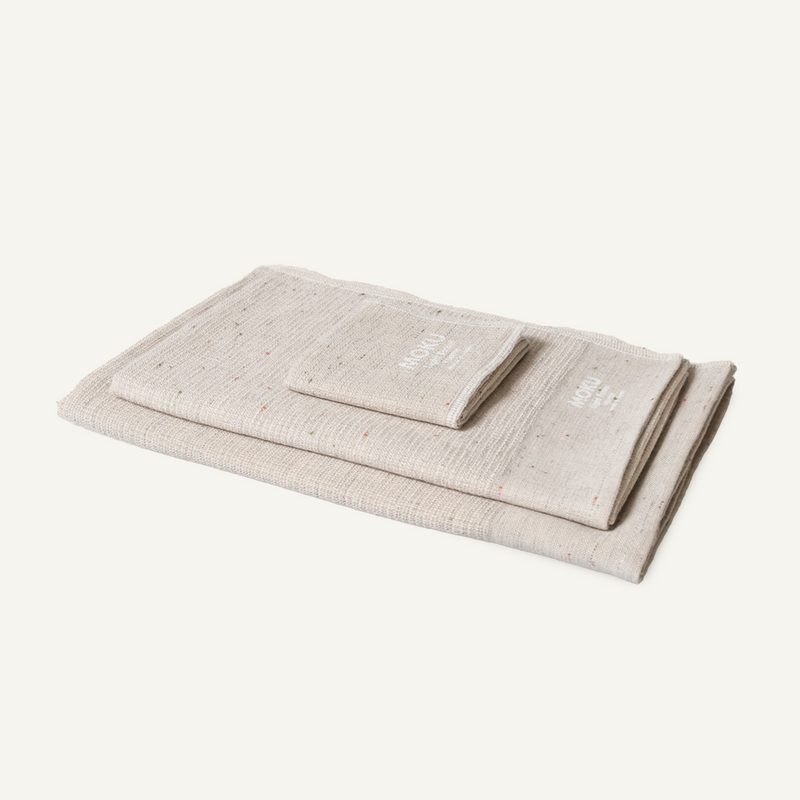 Three folded Moku Light Towels in natural speckled cotton, stacked with the smaller size on top