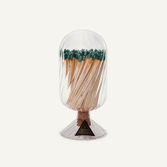 Skeem Helix Match Cloche with evergreen-tipped matches visible through hand-blown glass, cork stopper, and a fluted base