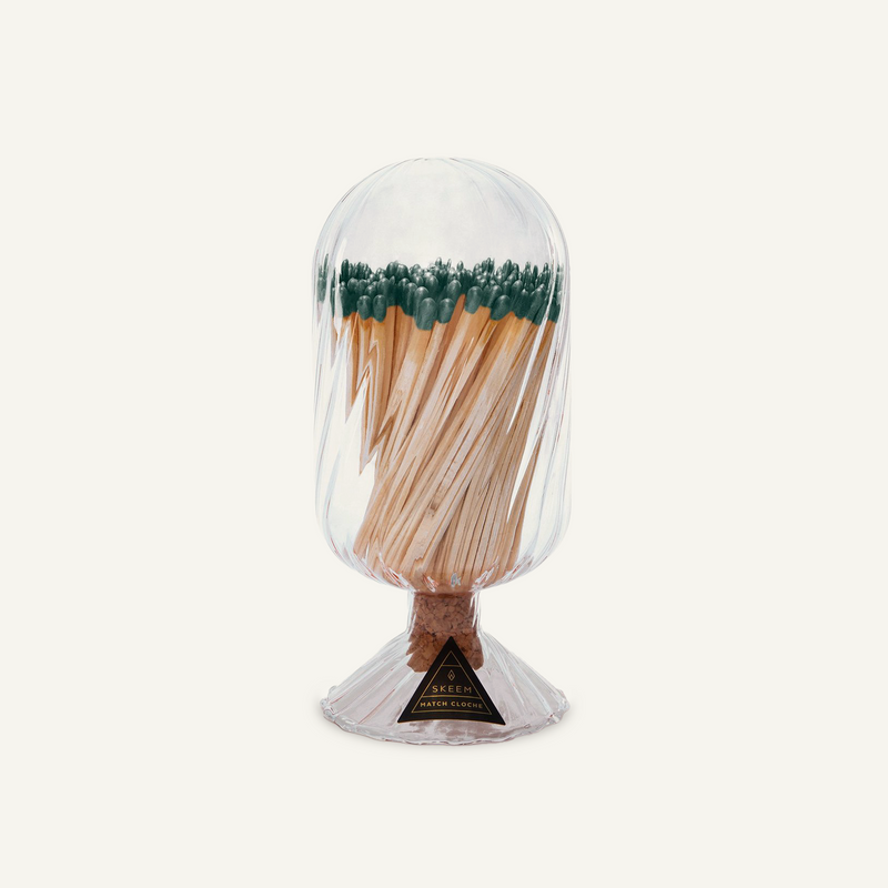 Skeem Helix Match Cloche with evergreen-tipped matches visible through hand-blown glass, cork stopper, and a fluted base
